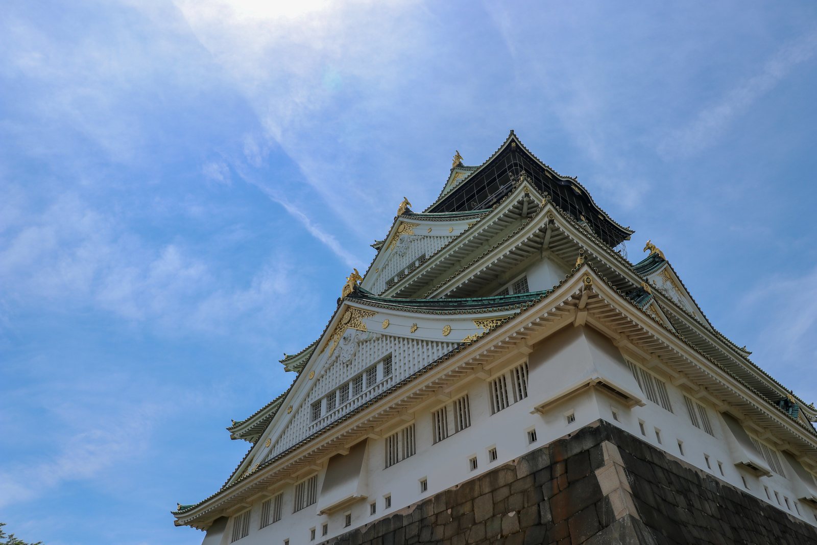 Osaka Castle rising above its stone base under a blue sky.