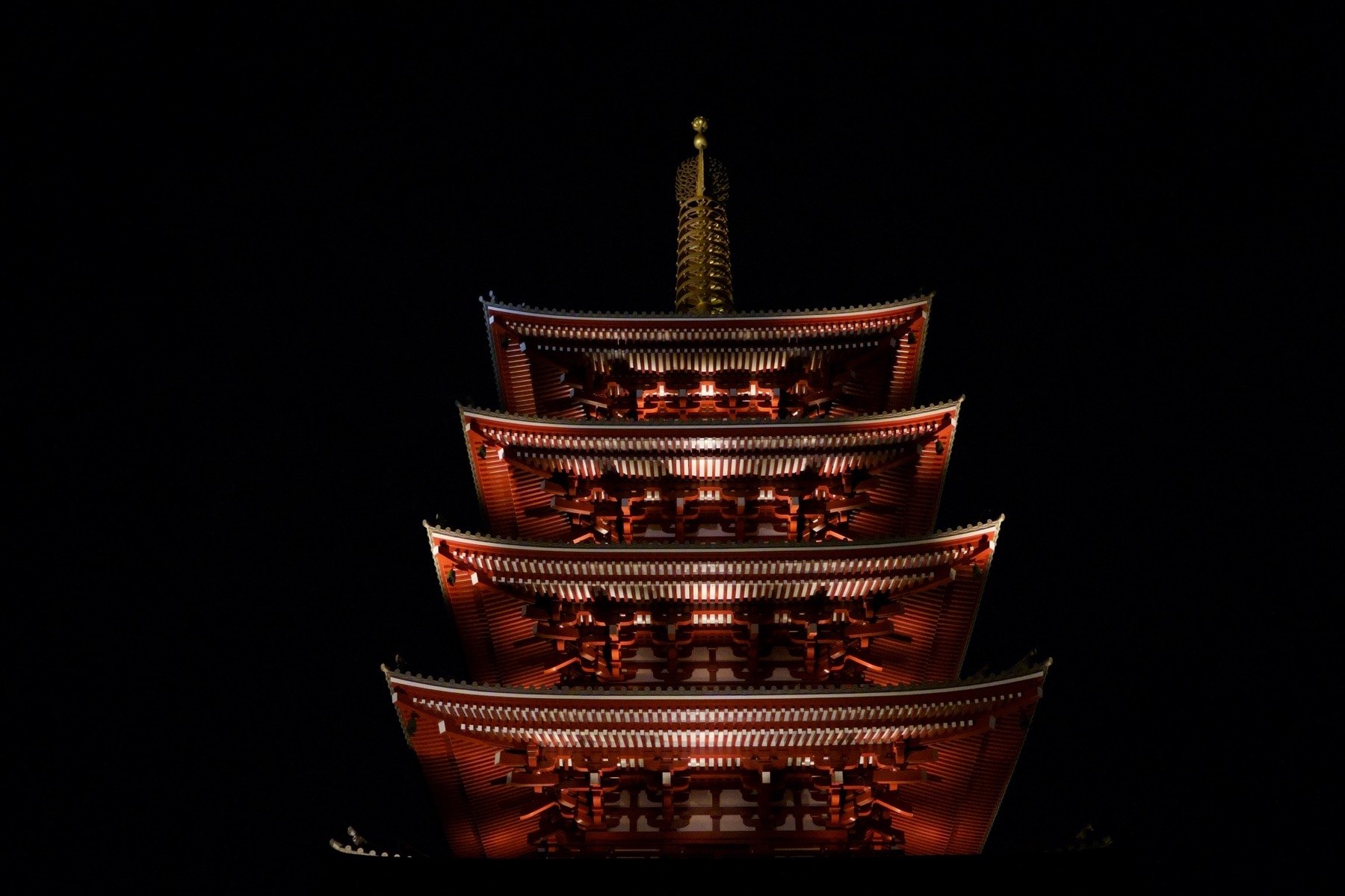 A lit temple pagoda in Asakusa against a black night sky.